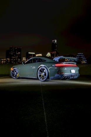 A sleek sports car with enhanced lighting and vibrant colors against a city backdrop at dusk.