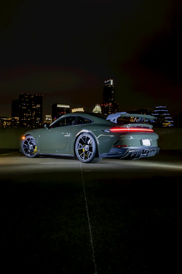 A sleek, shiny Japanese sports car parked in front of a modern Tokyo cityscape at dusk.