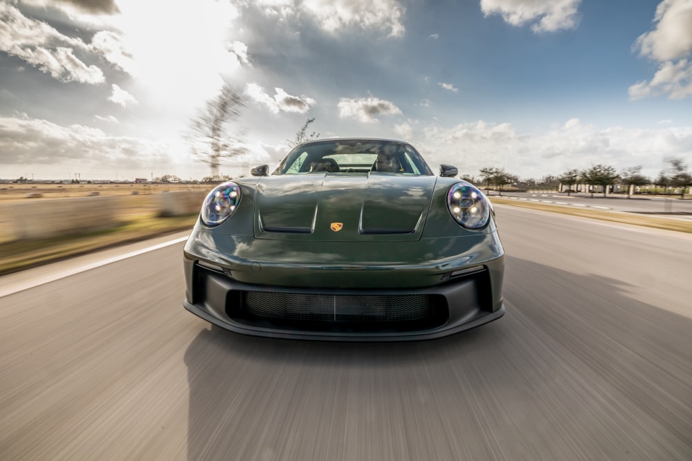 a green sports car driving down the road