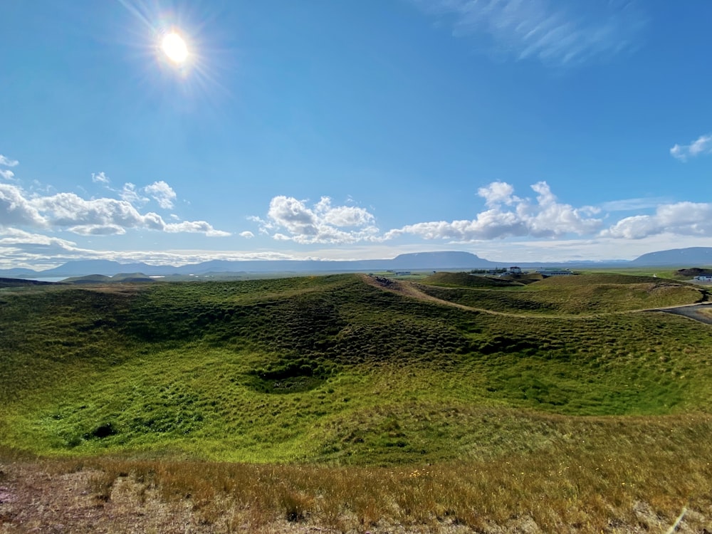 the sun is shining over a grassy hill