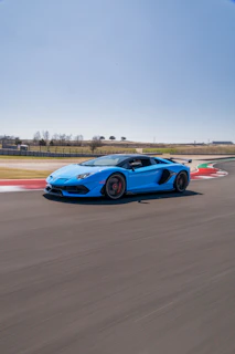A sleek motorsport car speeding on a coastal race circuit under clear skies.