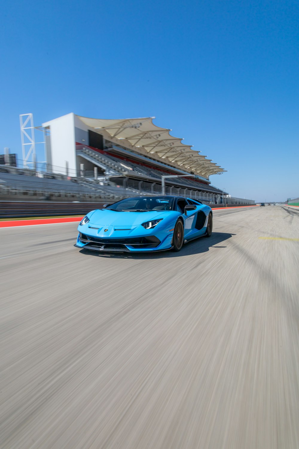 a blue sports car driving down a race track