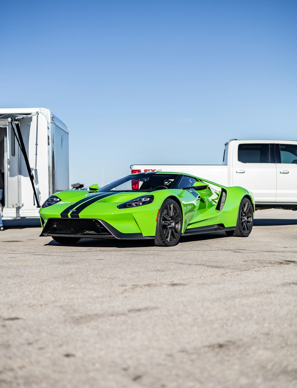 a lime green sports car parked next to a white truck