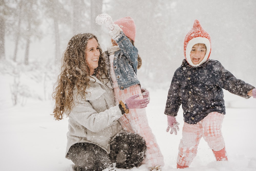 a woman and two children playing in the snow