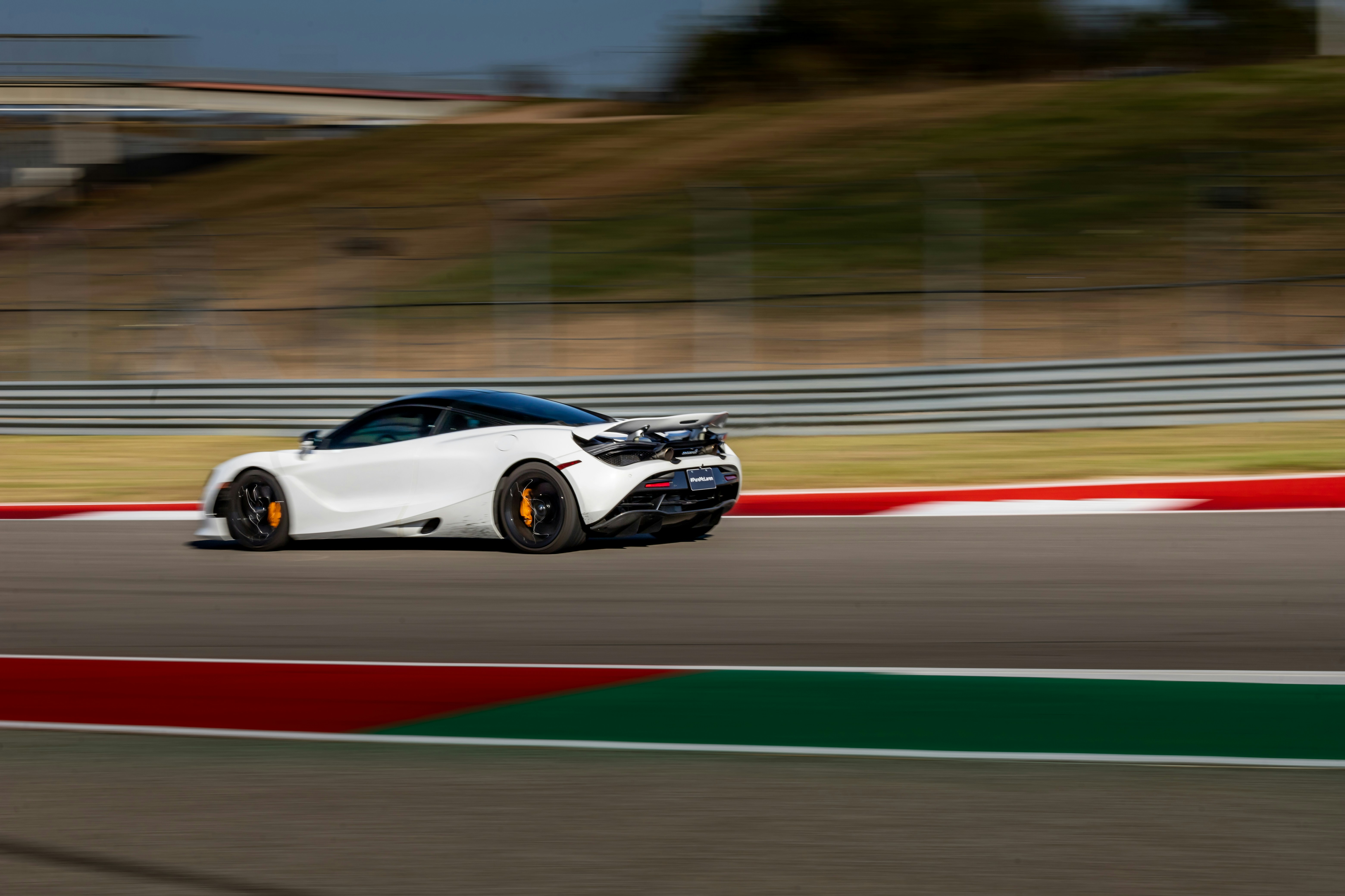 A white sports car driving down a race track photo – Free Vehicle Image ...