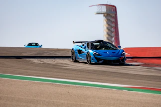 A colorful RC car zooming across a racetrack under a bright blue sky.