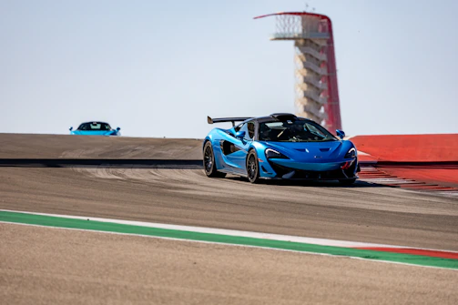 A colorful RC car zooming across a racetrack under a bright blue sky.