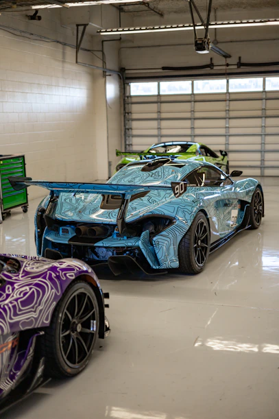 two race cars parked in a garage next to each other
