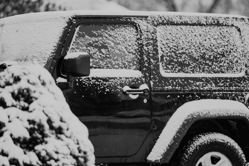 a black and white photo of a jeep covered in snow