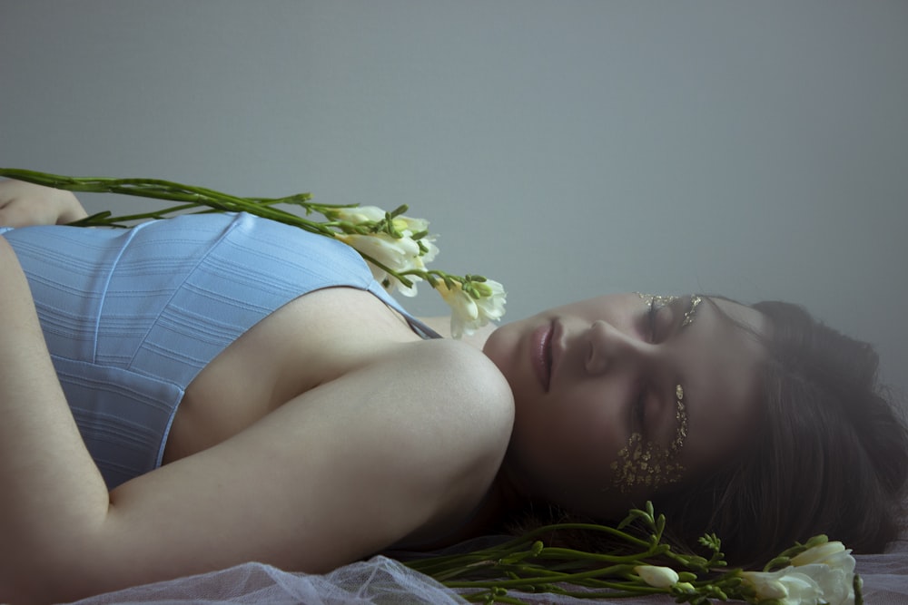 a woman laying on a bed with flowers in her hair