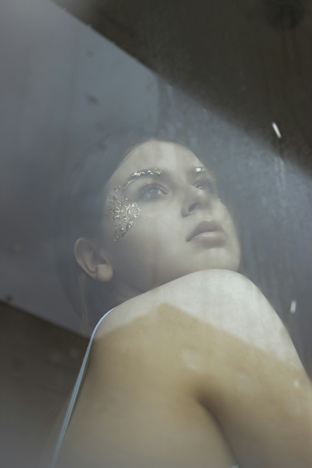 a woman with glitter on her face looking out a window
