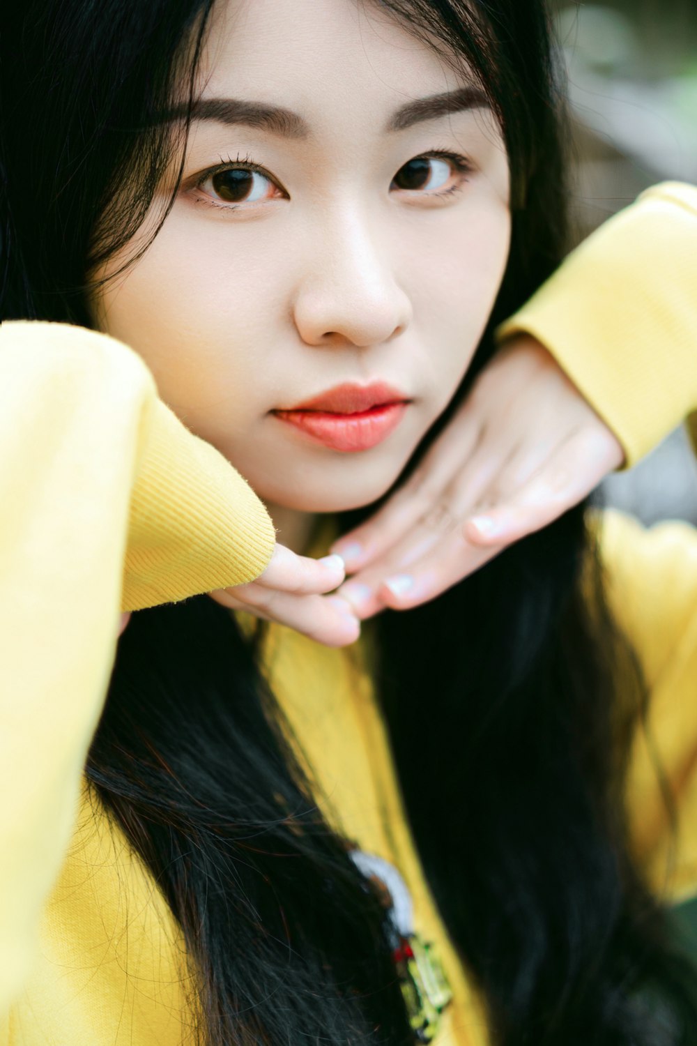 a woman with long black hair wearing a yellow sweater