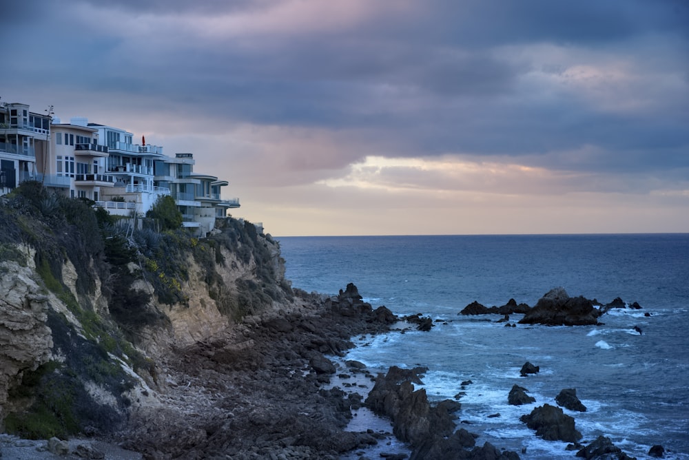 a row of houses sitting on top of a cliff next to the ocean