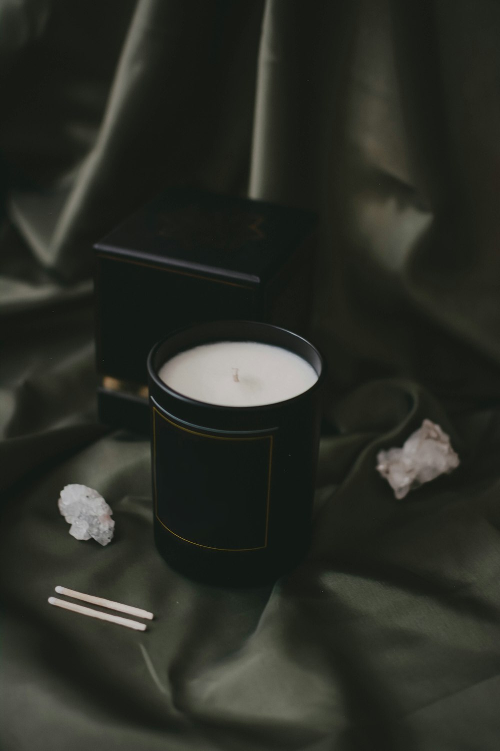 a candle sitting on top of a bed next to a box