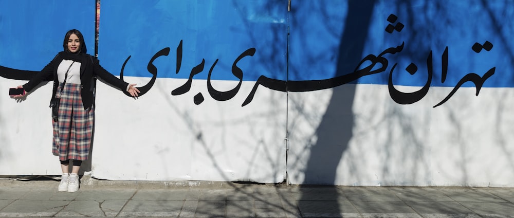 a woman standing in front of a blue and white wall