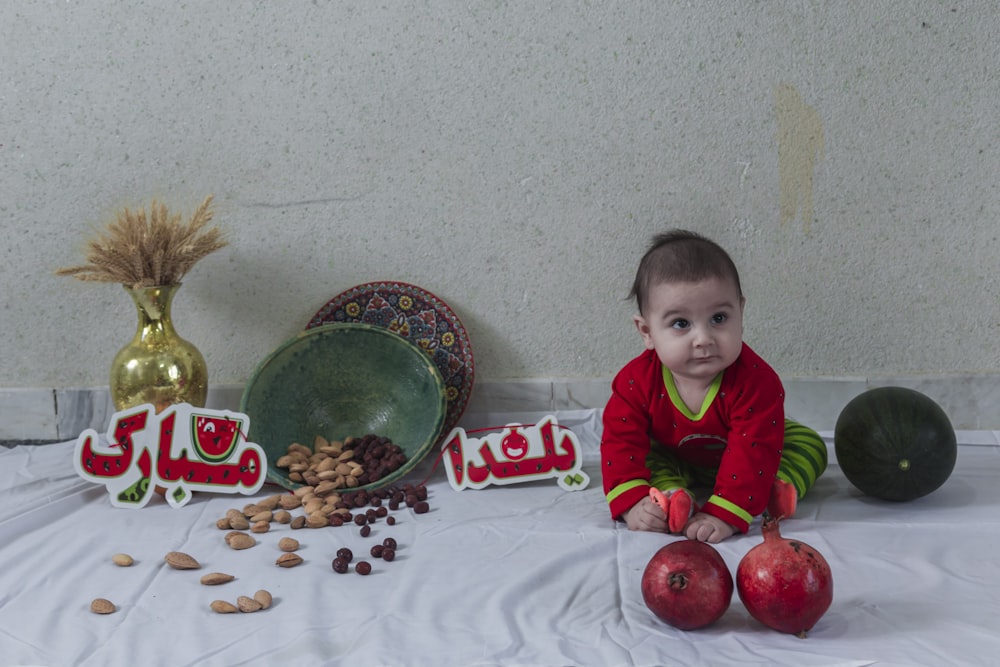un bébé assis sur une table avec des fruits et des noix