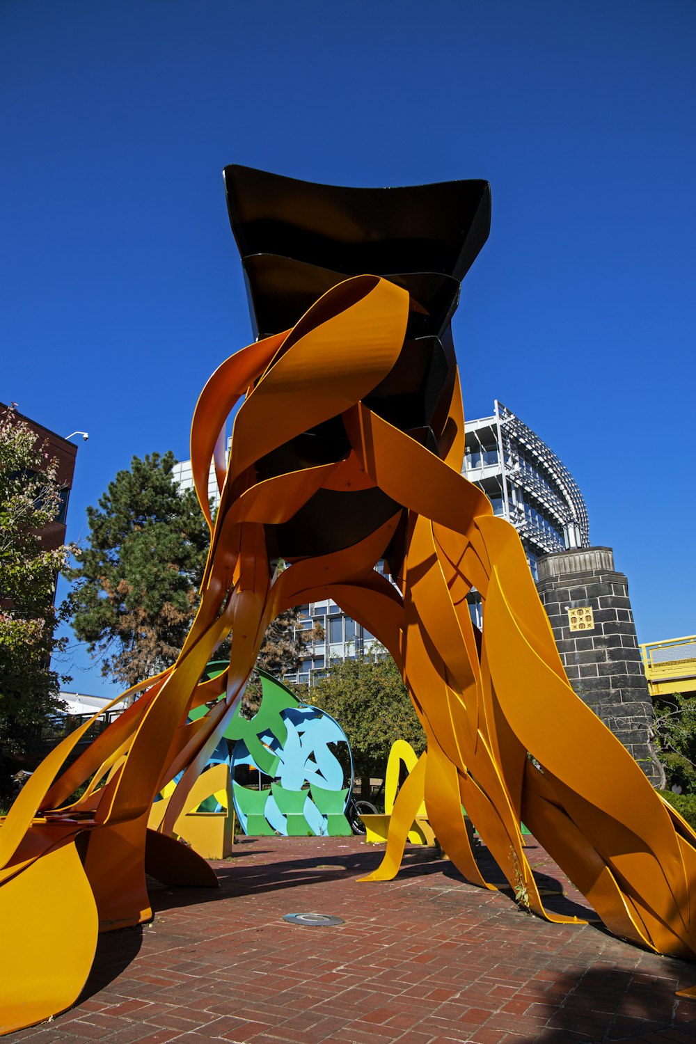 a large yellow sculpture sitting on top of a brick walkway