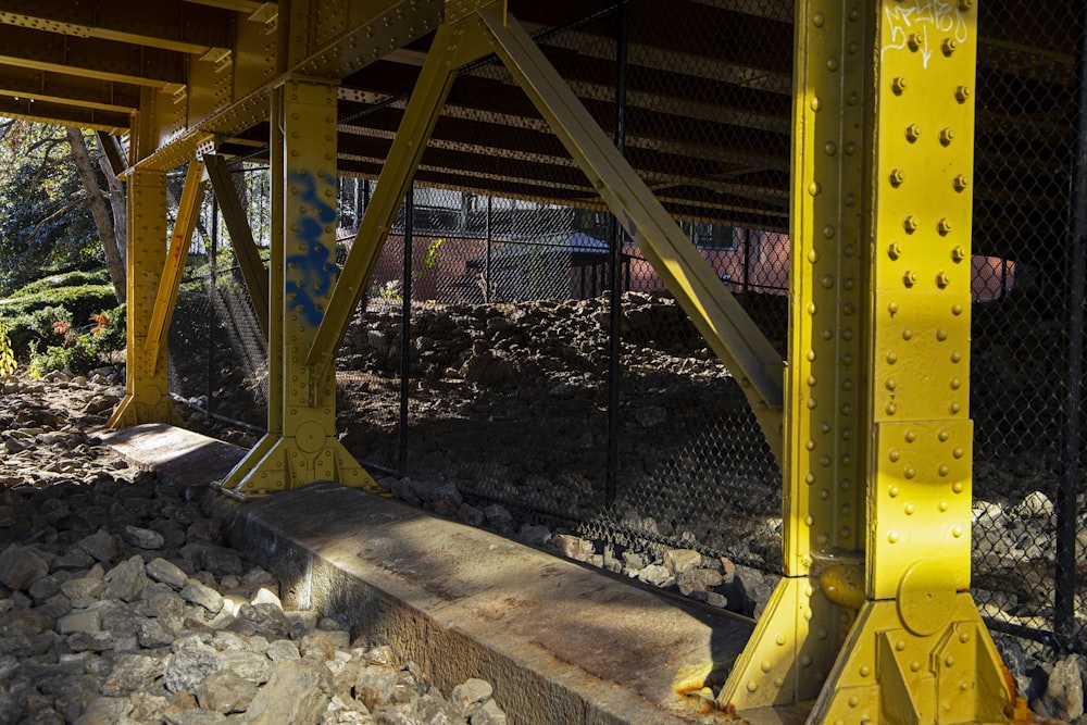 a yellow metal structure with rocks underneath it