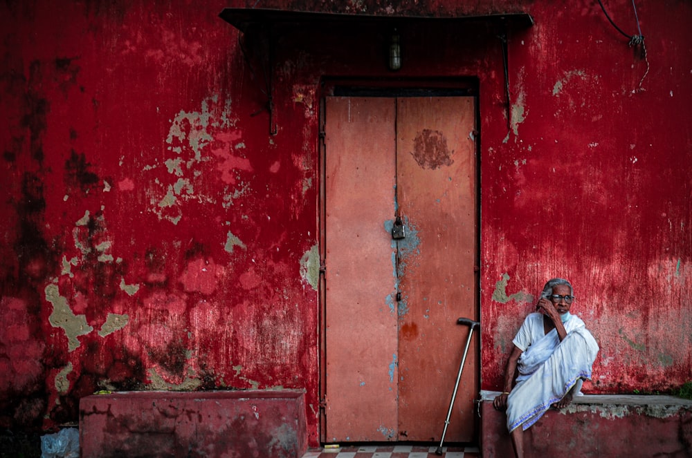 a man sitting in front of a red door
