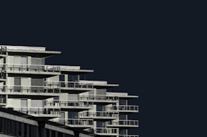 Wide shot of a contemporary residential complex with clean geometric shapes and dark tones