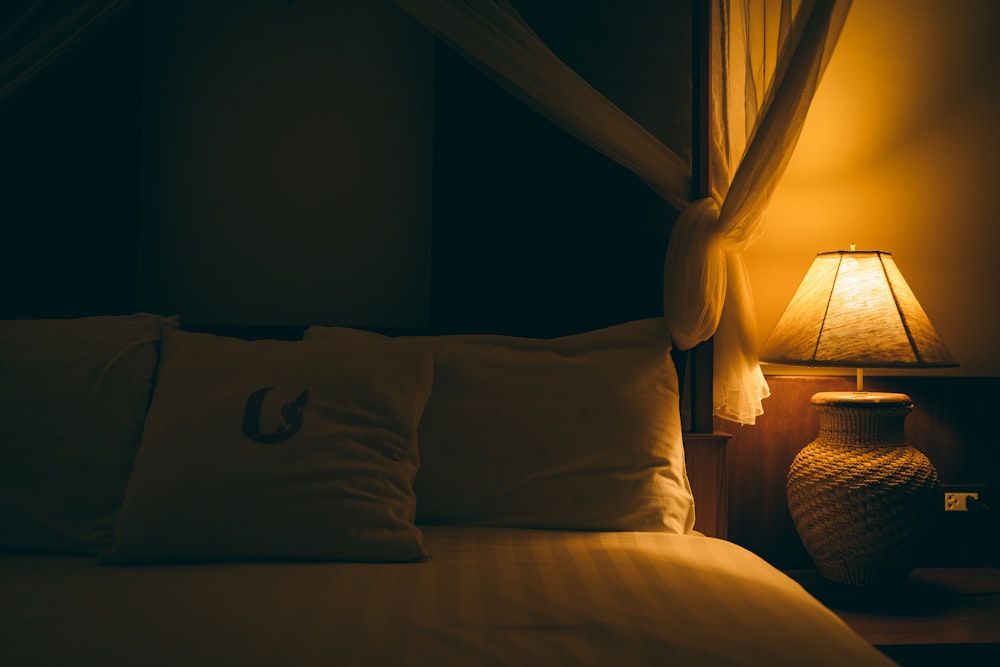 a bed with a white comforter and a lamp next to it