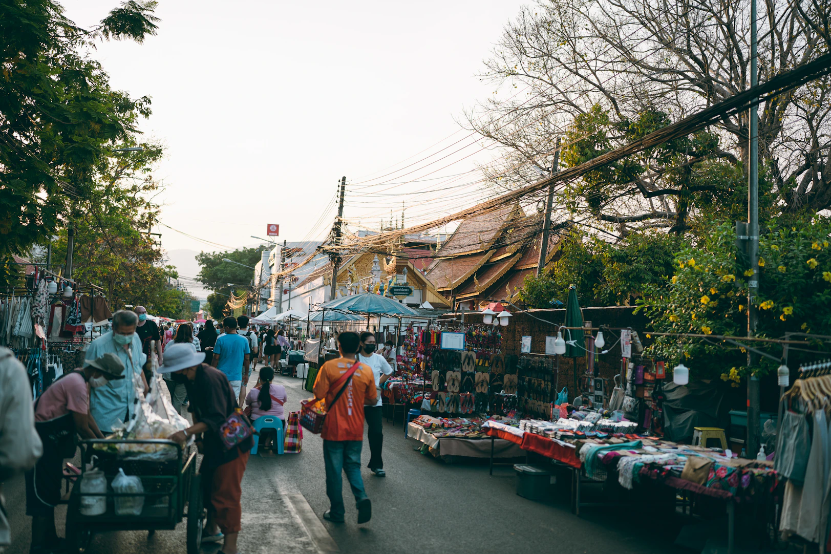 a group of people walking down a street next to a market