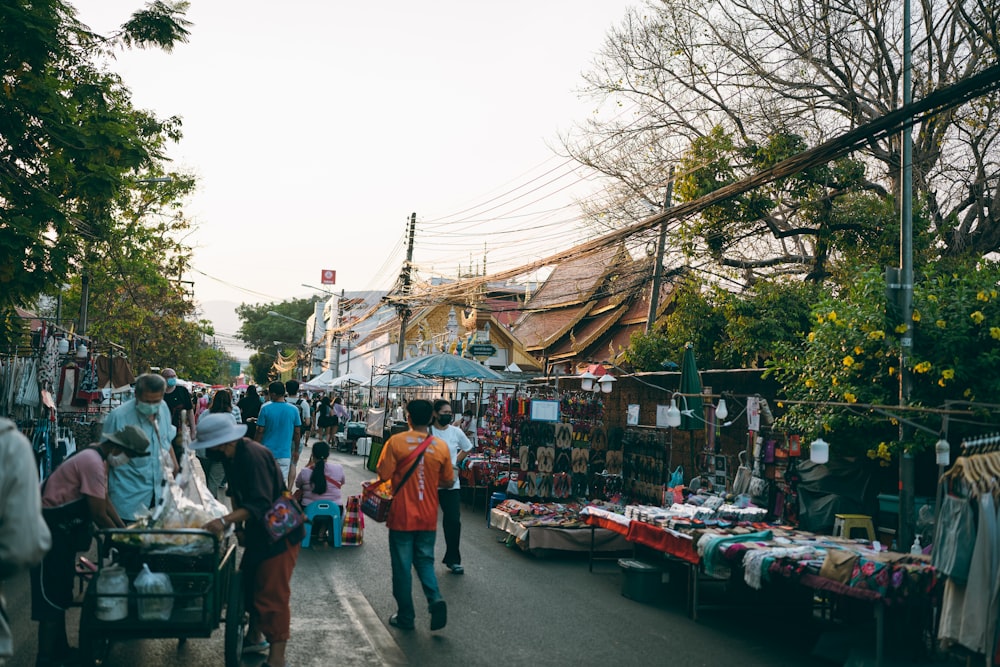 a group of people walking down a street next to a market