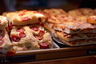 Slices of focaccia and pizza with visible cherry tomato toppings are arranged on a baking tray.