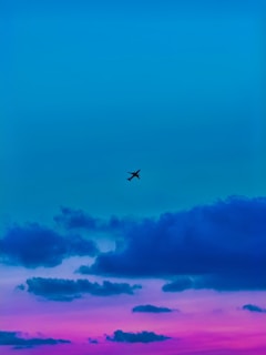 a plane flying in the sky at sunset