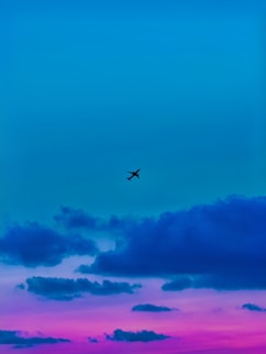 a plane flying in the sky at sunset