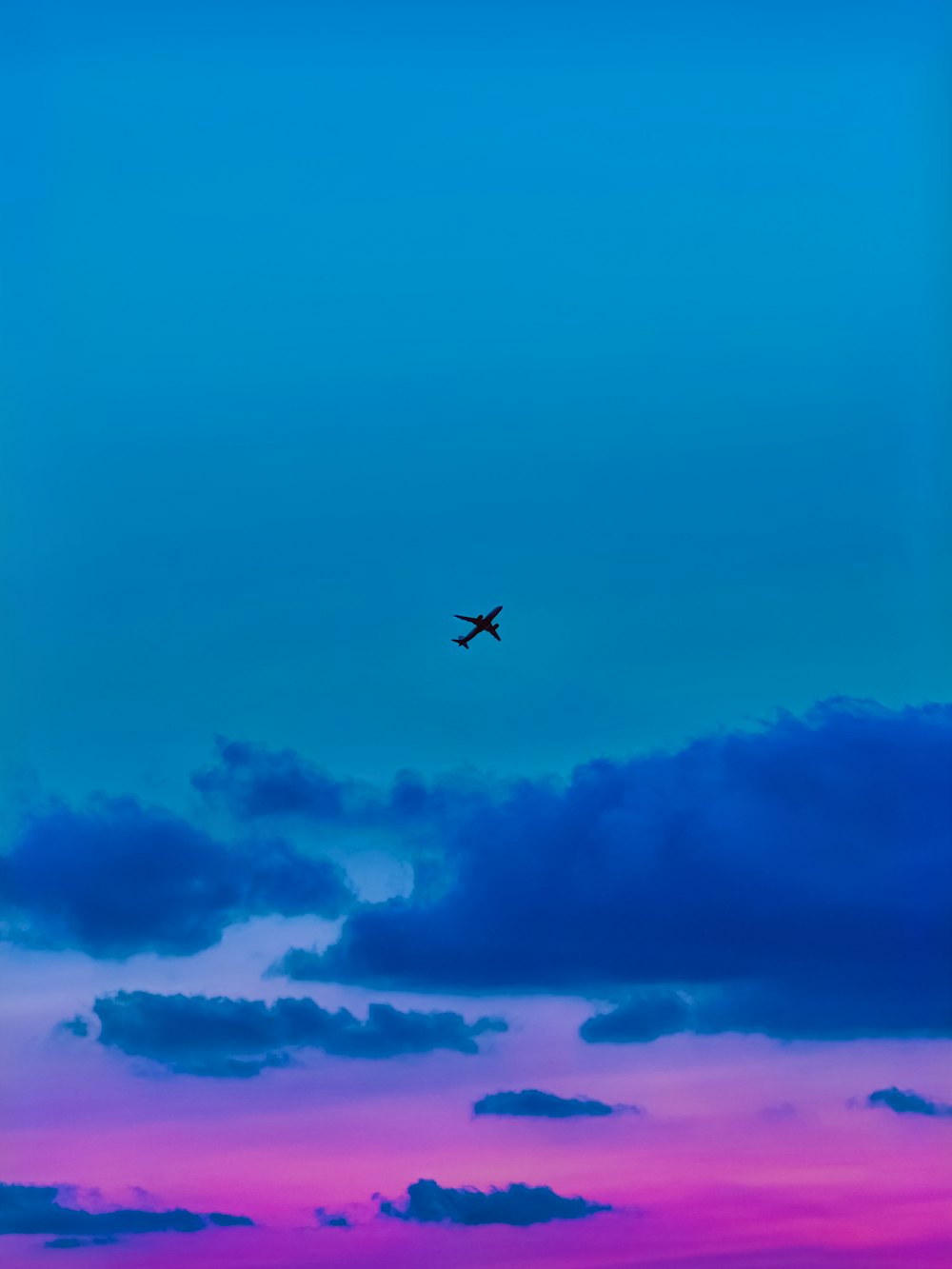 a plane flying in the sky at sunset