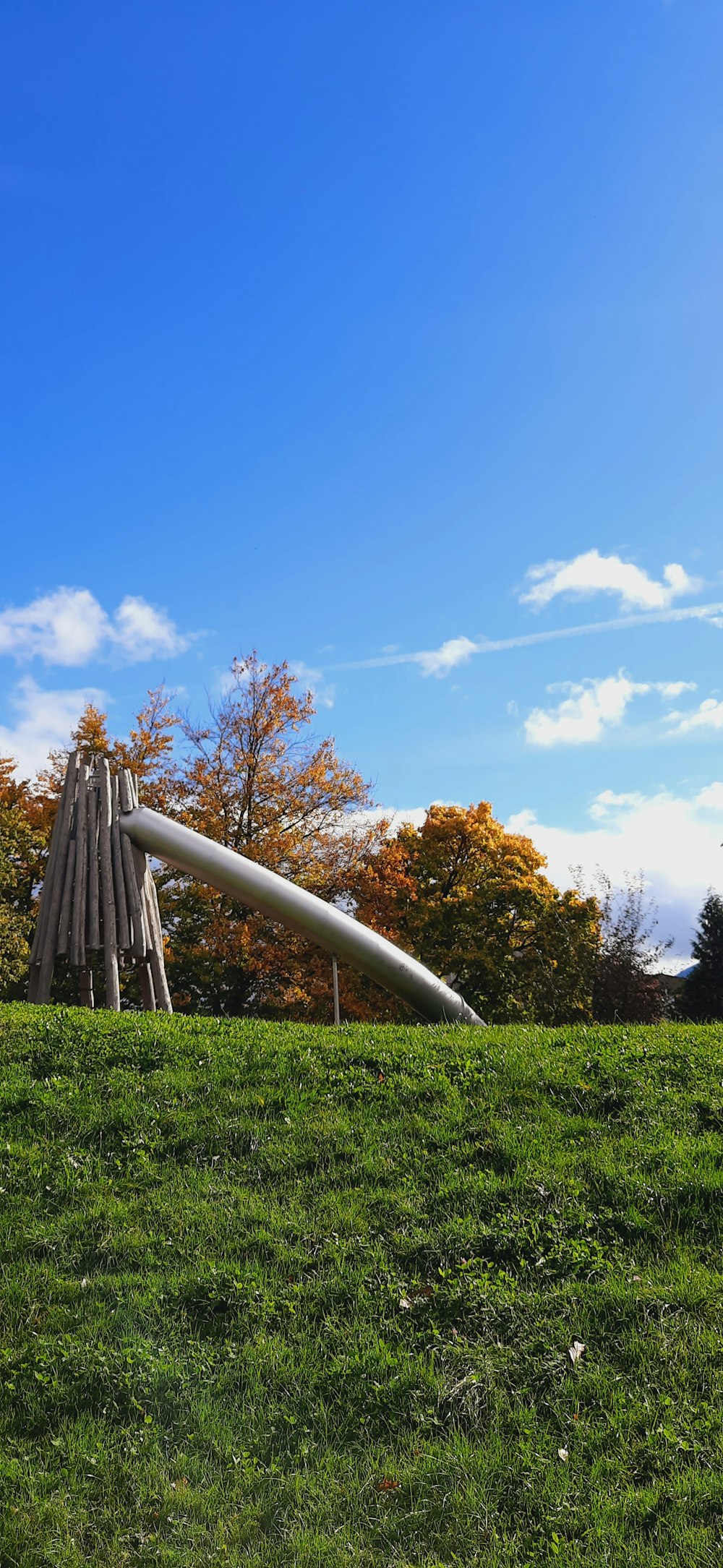 a wooden structure in the middle of a grassy field