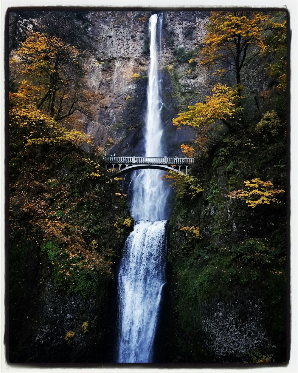 a large waterfall with a bridge over it