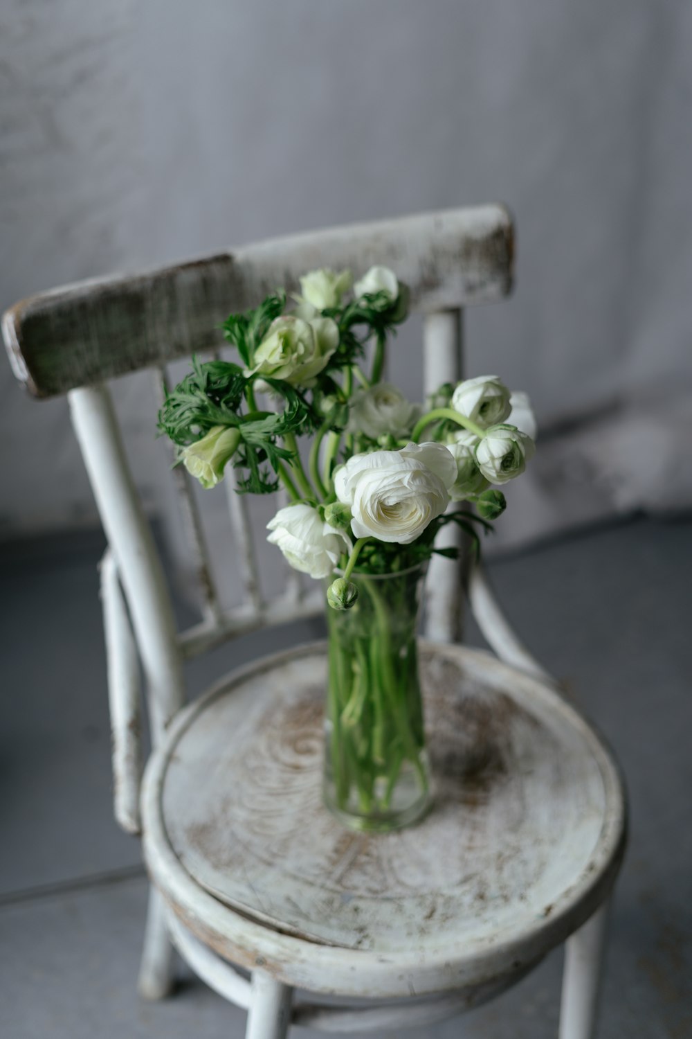 a white chair with a vase of flowers on it