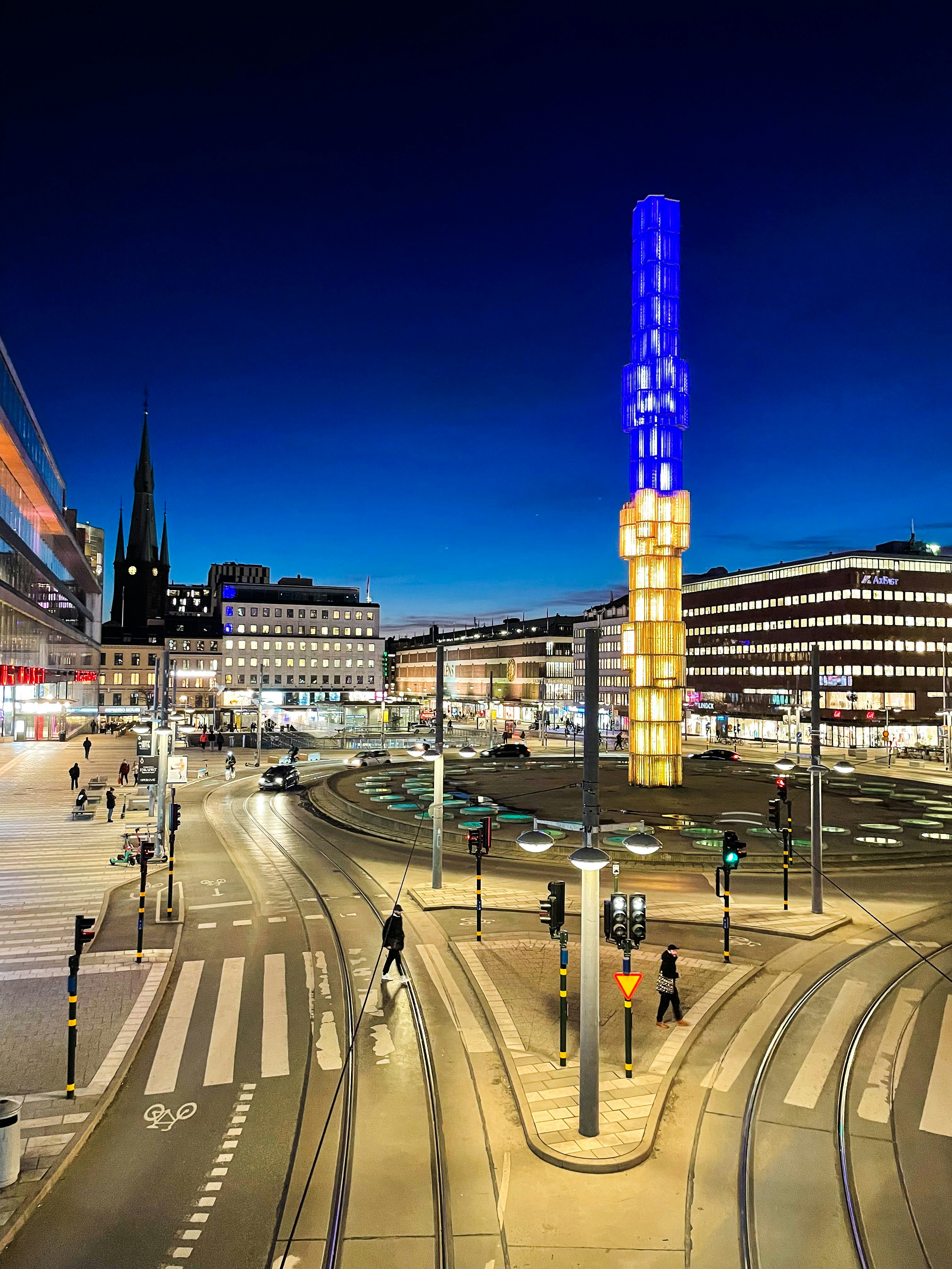a city street at night with a tall building in the background