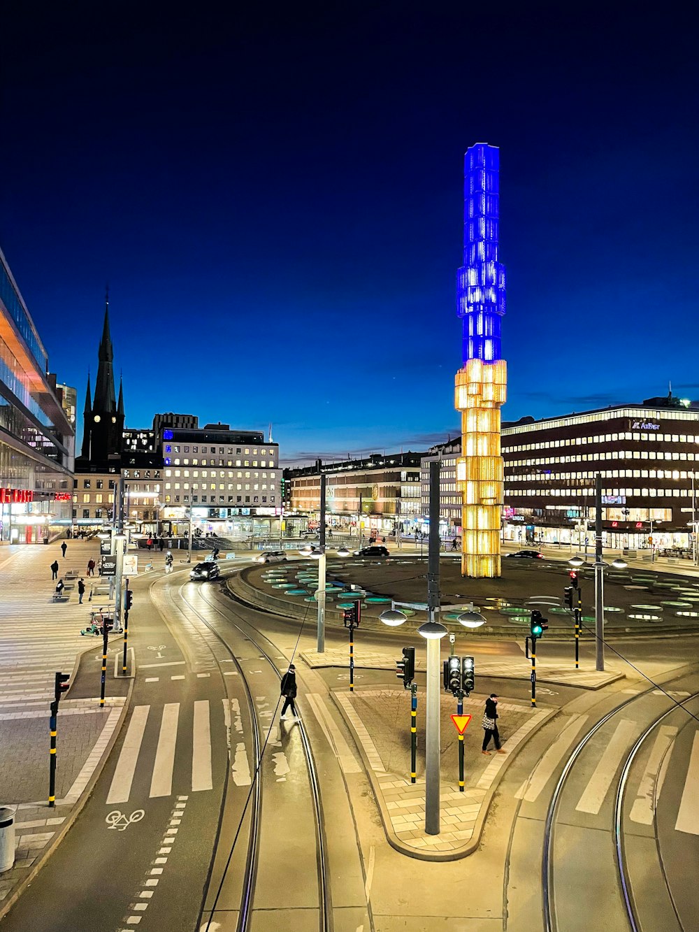 a city street at night with a tall building in the background