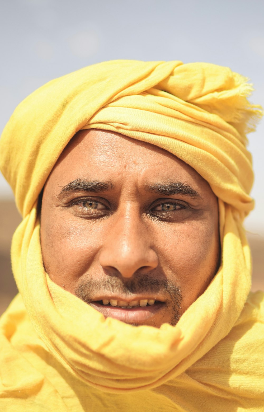 a man in a yellow turban smiles for the camera