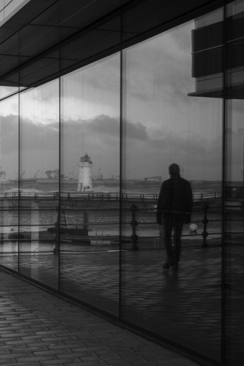 a man walking down a sidewalk next to a tall building