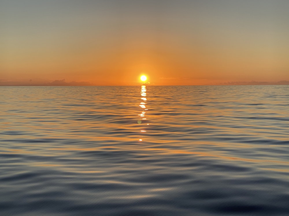 a large body of water with a sunset in the background