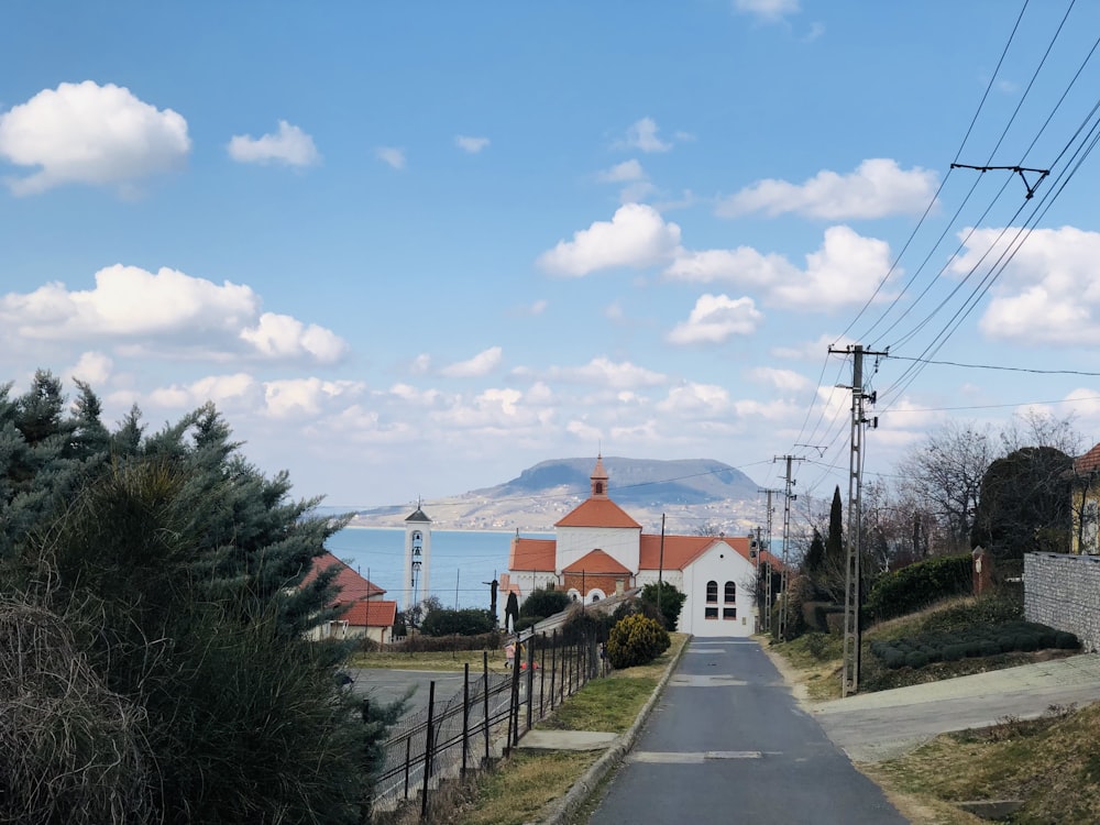 a road with a church and a body of water in the background