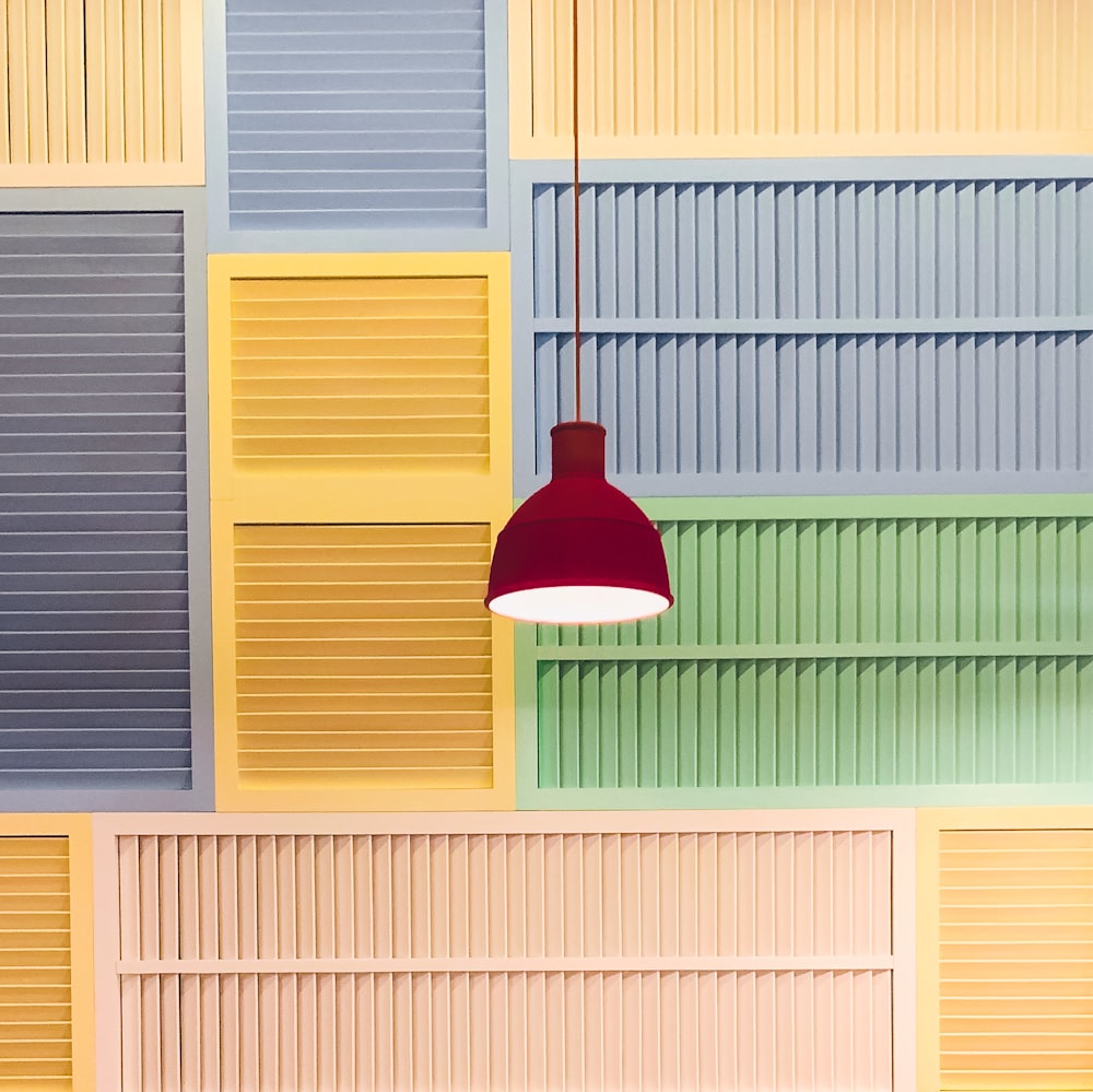 a lamp hanging from a ceiling in front of a multicolored wall