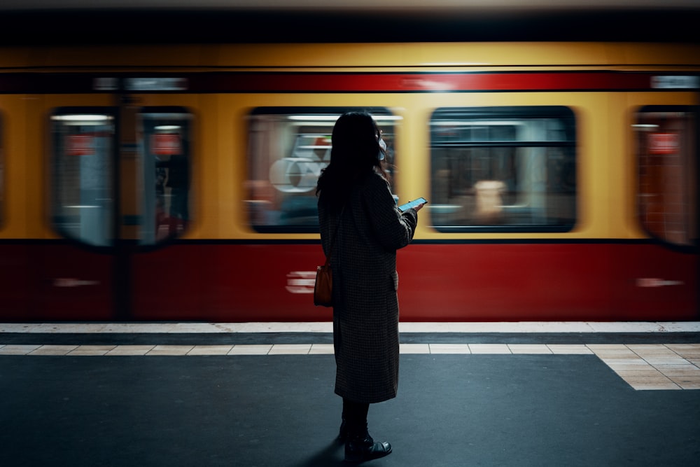 a woman standing in front of a train at a train station