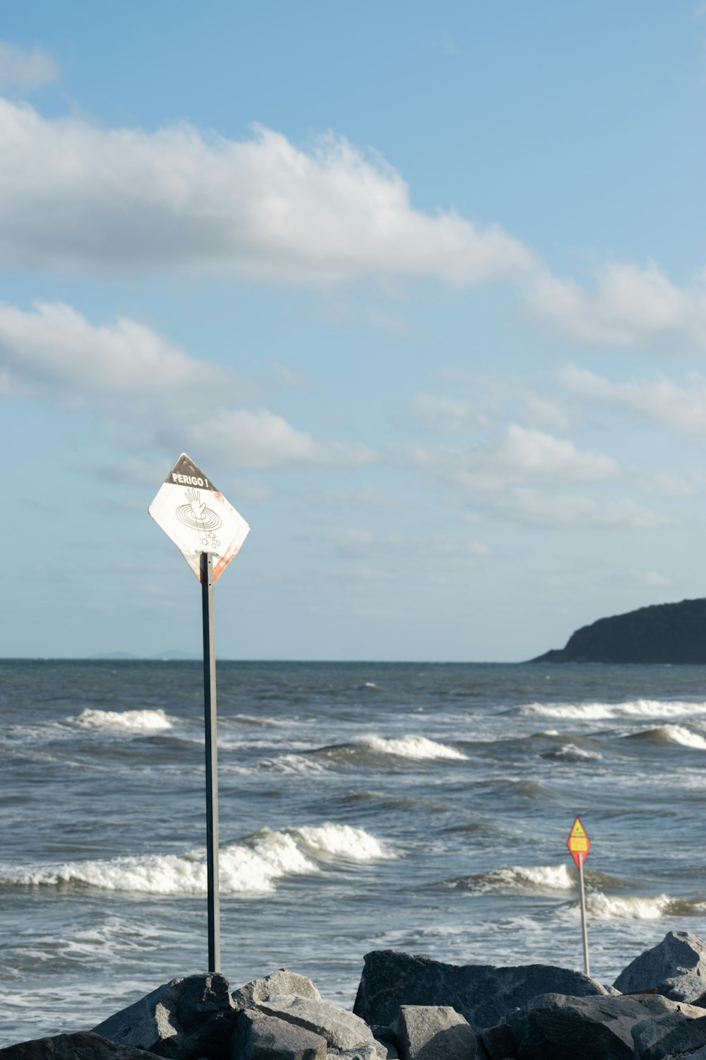 a sign on a rock near the ocean