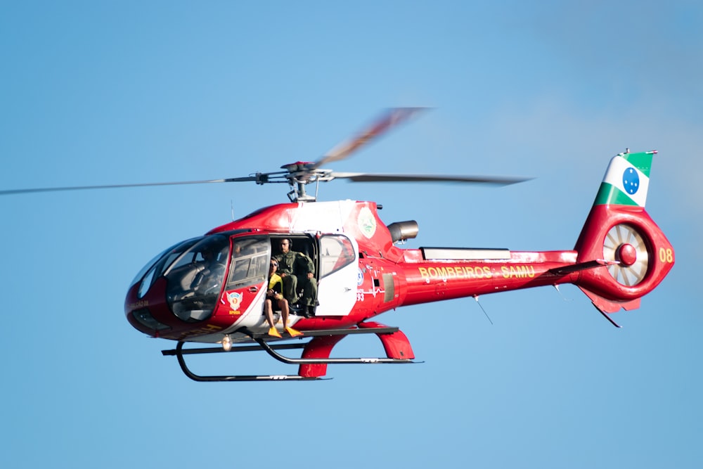 a red helicopter flying through a blue sky