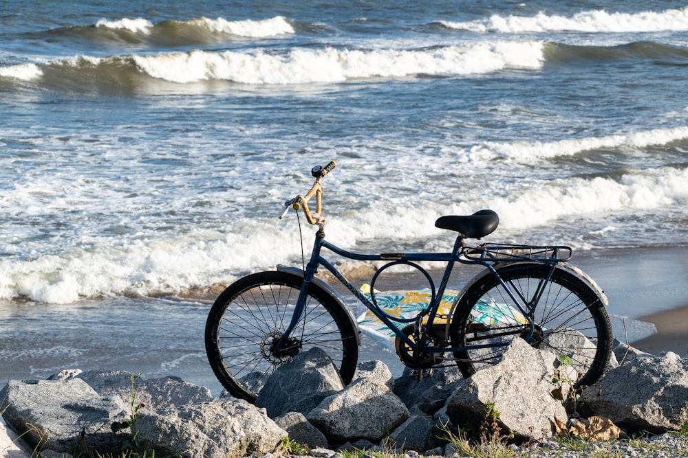 a bicycle parked on a rock near the ocean