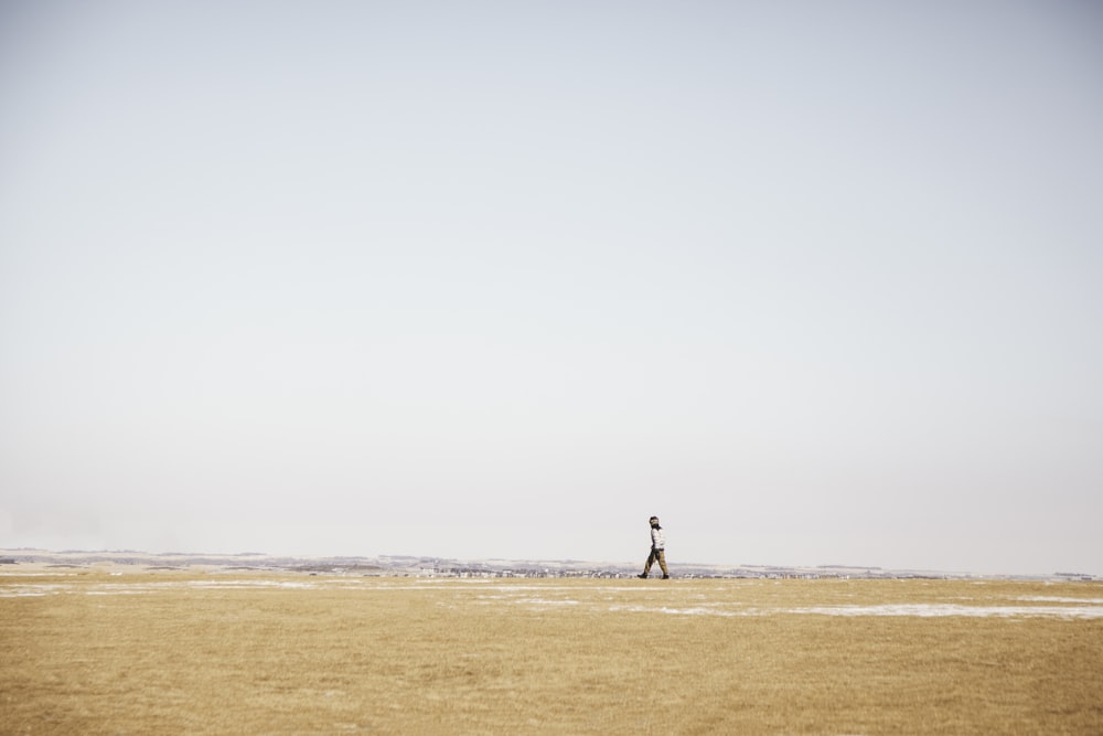 a person walking across a field with a kite in the sky