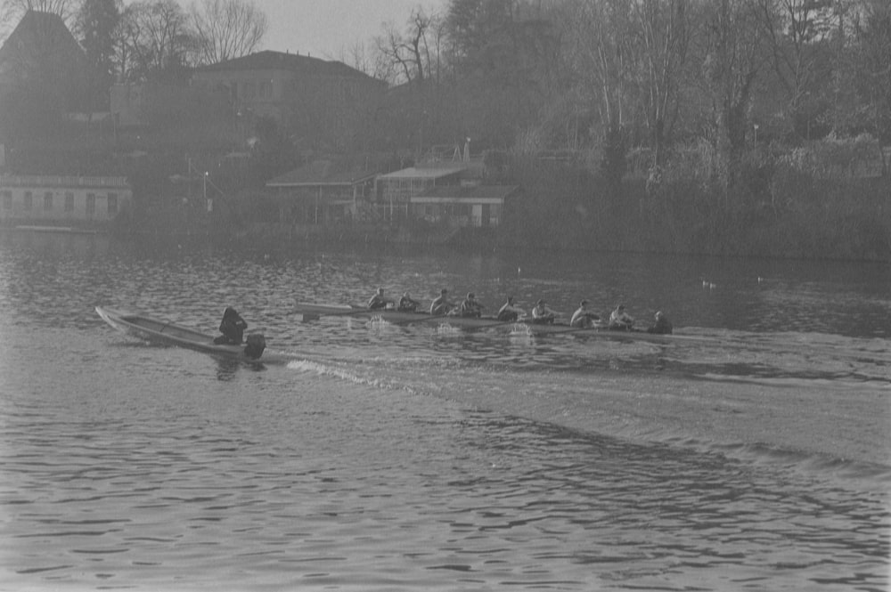 a black and white photo of a group of people rowing a boat