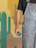 A person wearing paint-splattered denim overalls holds a green paintbrush. The background includes a painted desert scene featuring stylized cacti and a canyon with colors ranging from beige to orange.