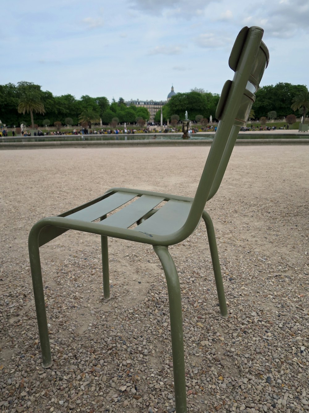 une chaise verte posée au-dessus d’un champ de gravier