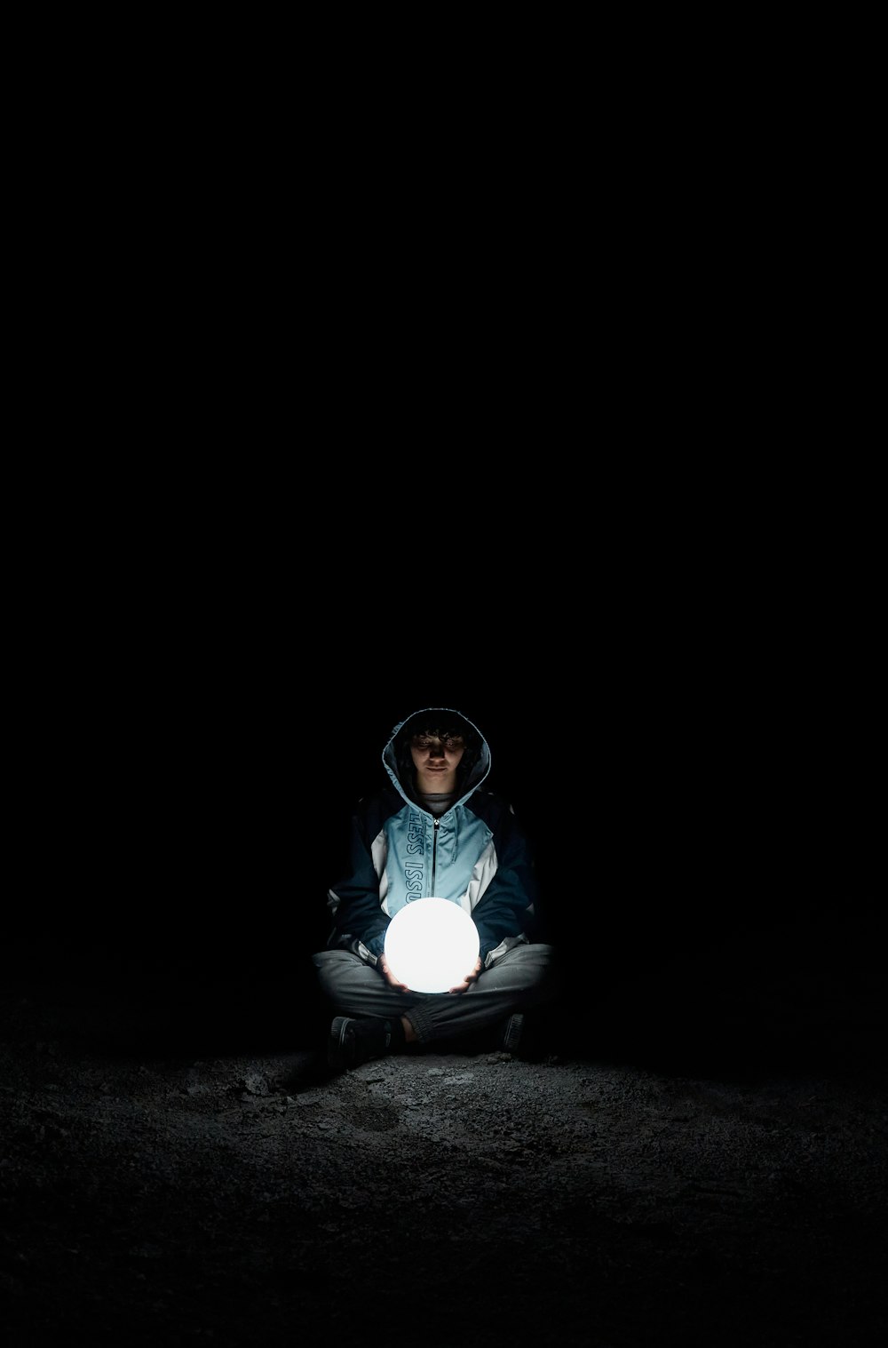 a man sitting in the dark holding a glowing ball